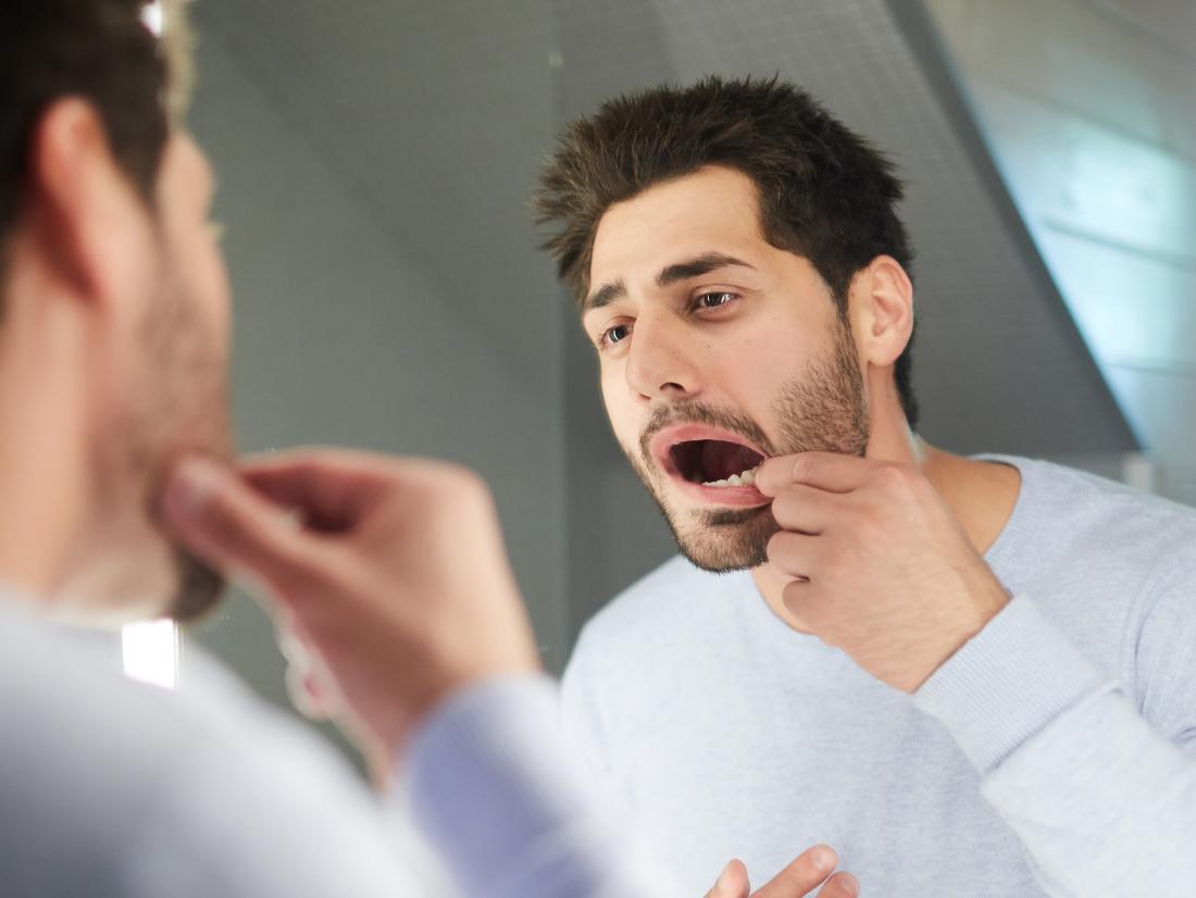 a man trying to feel the soft palate in his mouth with his finger. 