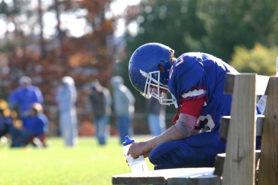 Injured football player sitting on the bench