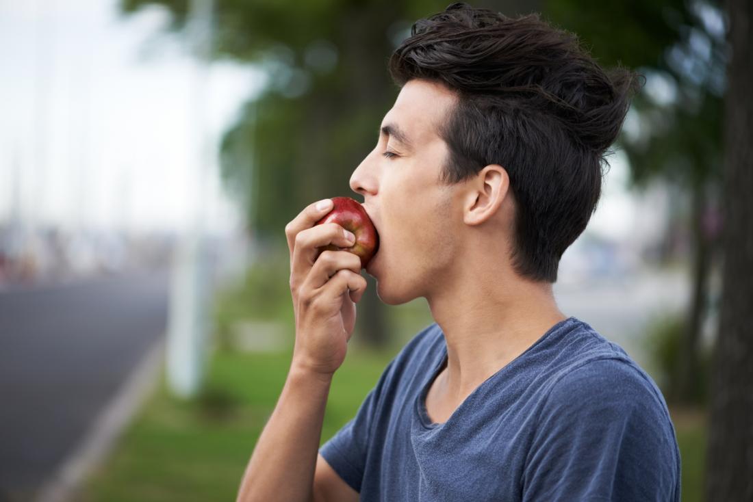 Man eating an apple outside.
