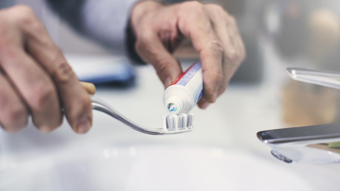 man putting toothpaste on a tooth brush