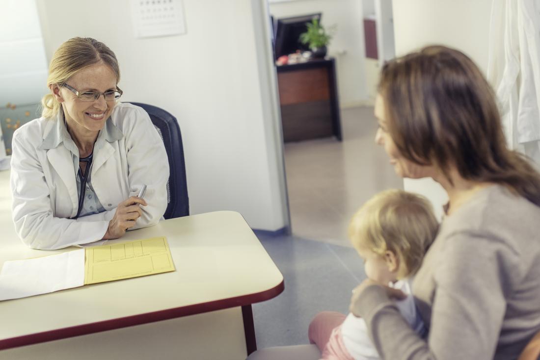 Pediatrician in office talking to mother and child patient.