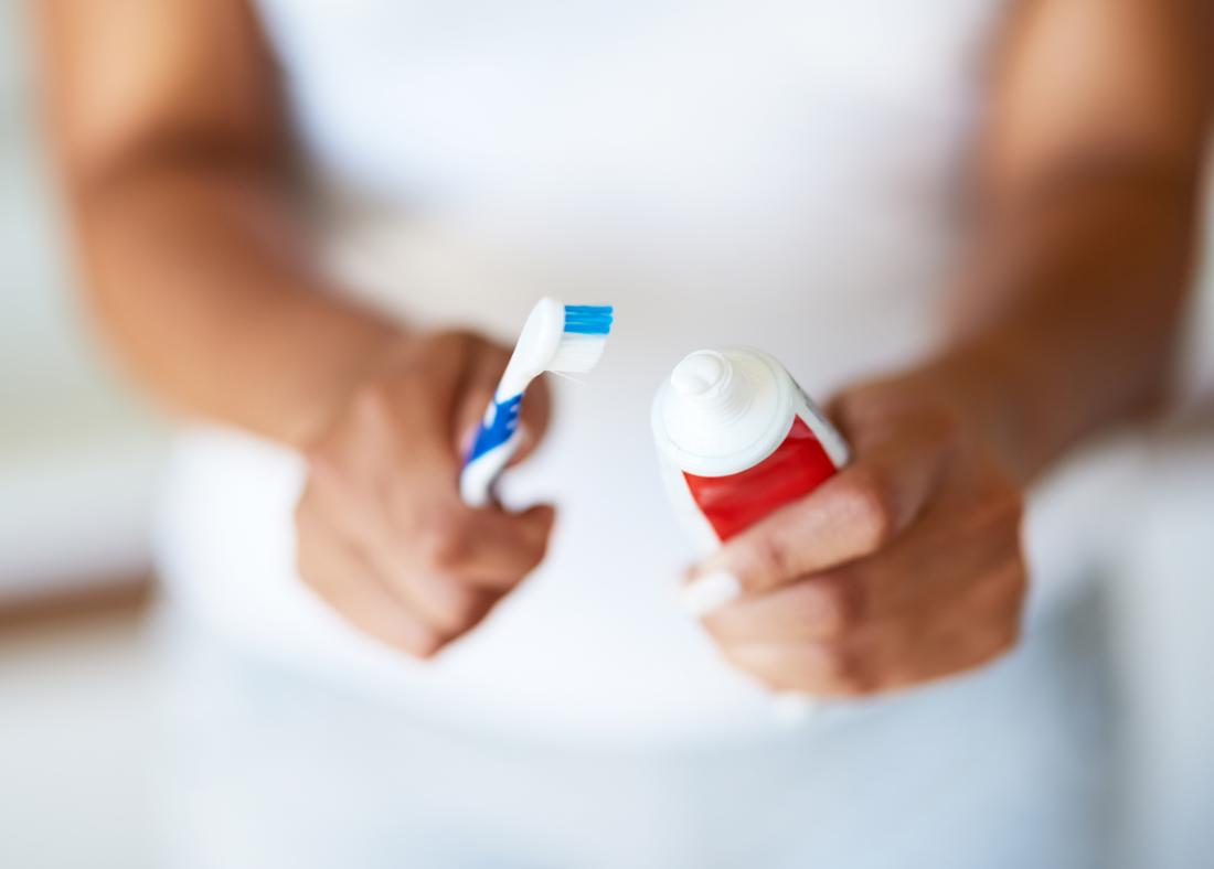 Person holding a toothbrush and toothpaste to help get rid of white gums