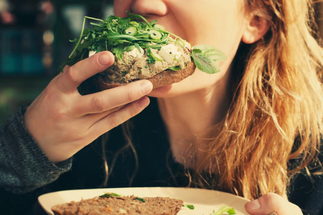 Woman eating veggie sandwich.