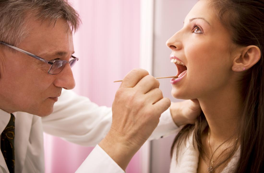 Woman having her tongue and throat inspected by doctor.