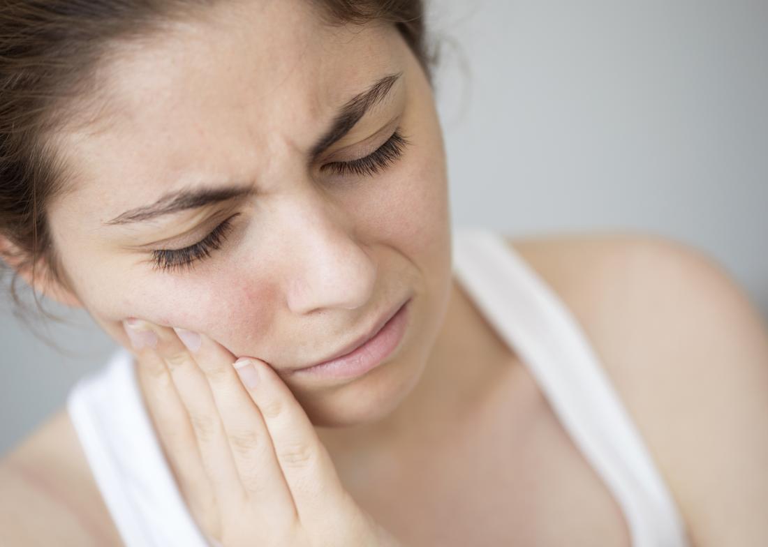 Woman holding cheek because of tooth pain