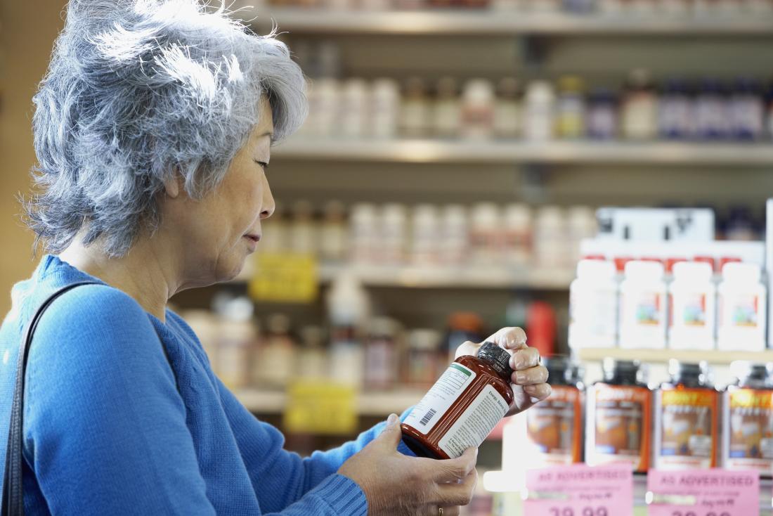 Woman reading label of supplement bottle in pharmacy